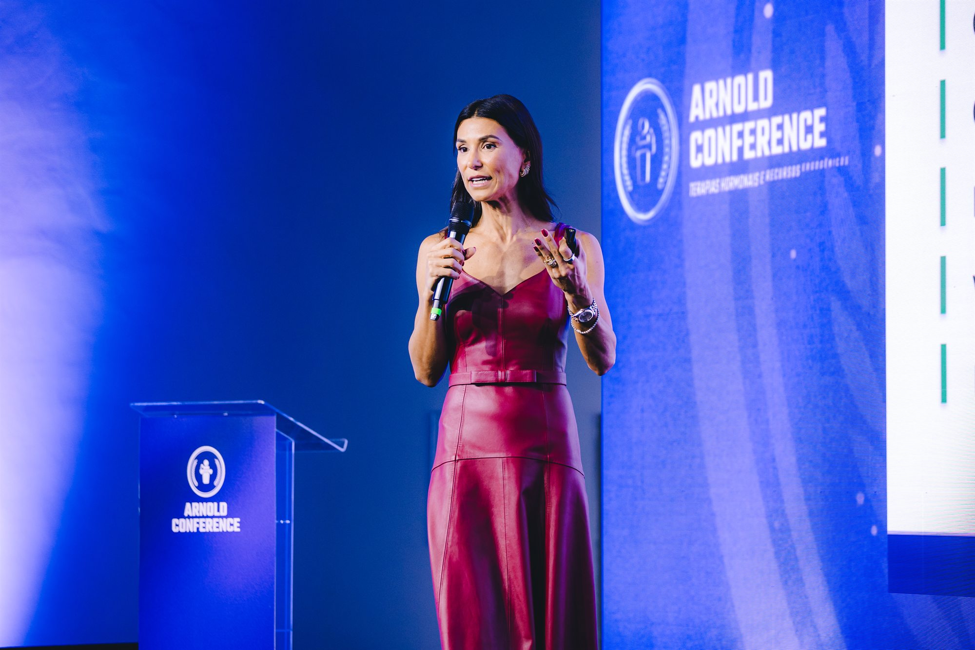 Alessandra Feltre falando ao microfone durante o Arnold Conference